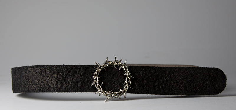 The Kranz (black) — the belt laid out flat on grey, spiked thorn-crown buckle at the centre