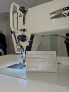 Cardholder salmon leather white — the silver cardholder standing on the bed of an industrial sewing machine in the atelier