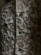 Cendre Cross Beige — close crop of the button placket, black crosses across the crinkled beige ash-texture surface