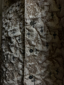 Cendre Cross Beige — close crop of the button placket, black crosses across the crinkled beige ash-texture surface