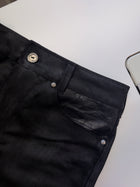 Bootcut Denim — close-up of the front pocket with black leather insert, button and rivet, laid flat on a white surface