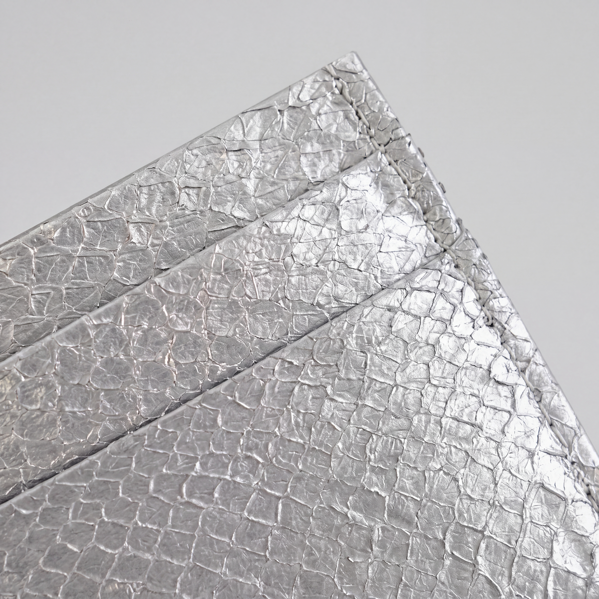 Cardholder salmon leather white — close crop of the upper corner, metallic salmon scale grain and stitched edge