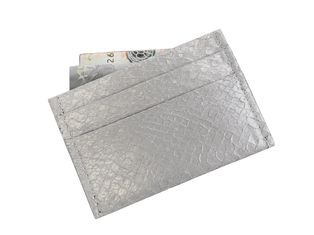 Cardholder salmon leather white — the silver cardholder tilted against white with banknotes tucked into the top slot