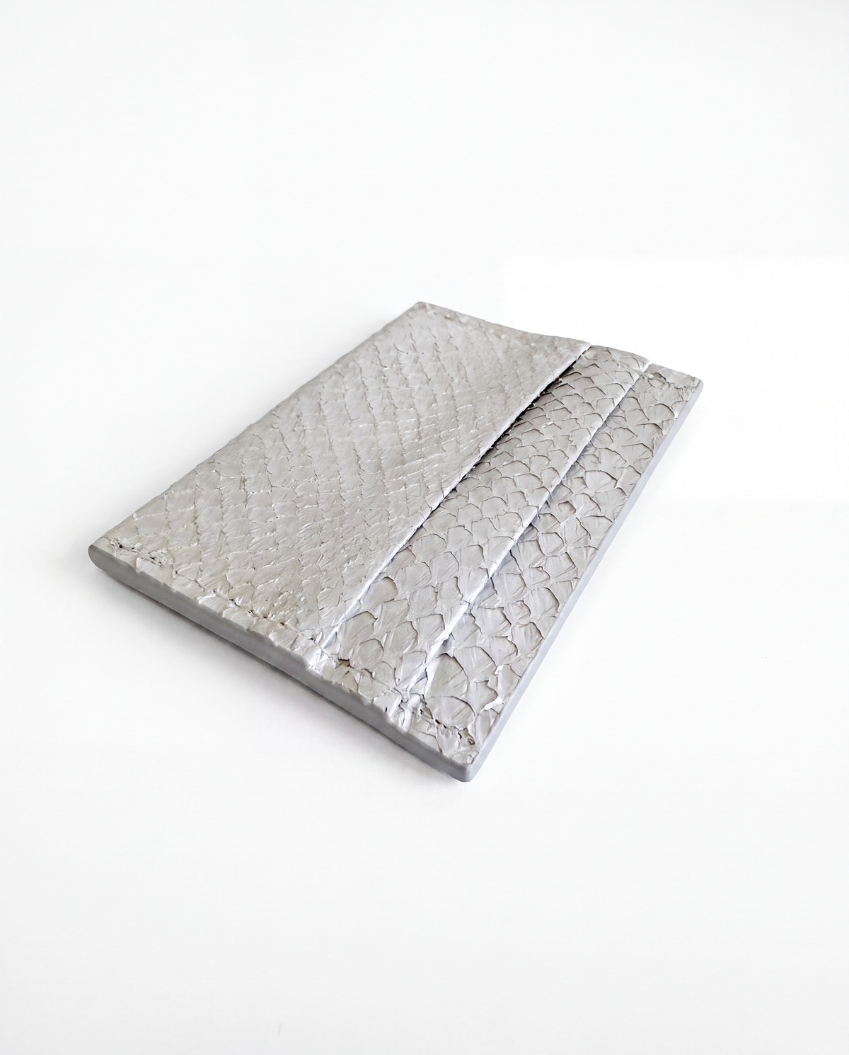 Cardholder salmon leather white — the silver cardholder lying flat at an angle on white, card slots along the upper edge