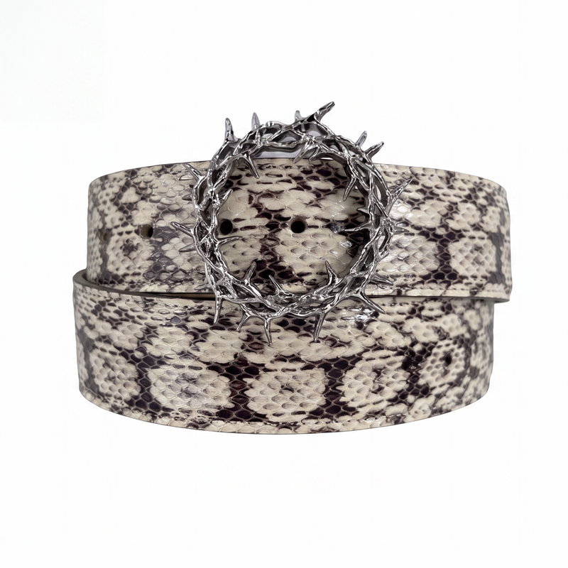 The Kranz Snakeskin white — cream and black python-patterned belt coiled on a white background, spiked thorn-crown buckle at the centre