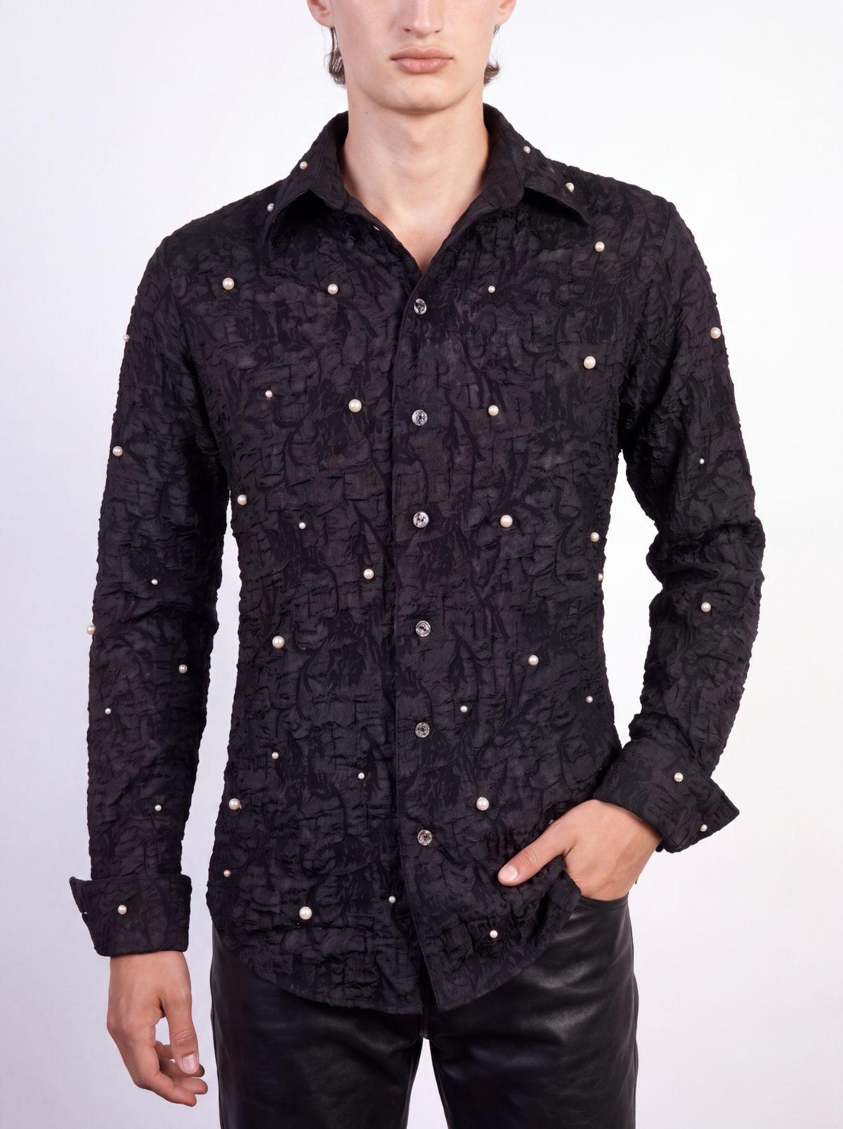 Pearl Cendre Shirt — male model from neck to thigh against a pale grey background, shirt worn open at the collar with black leather trousers, pearls across front and sleeves