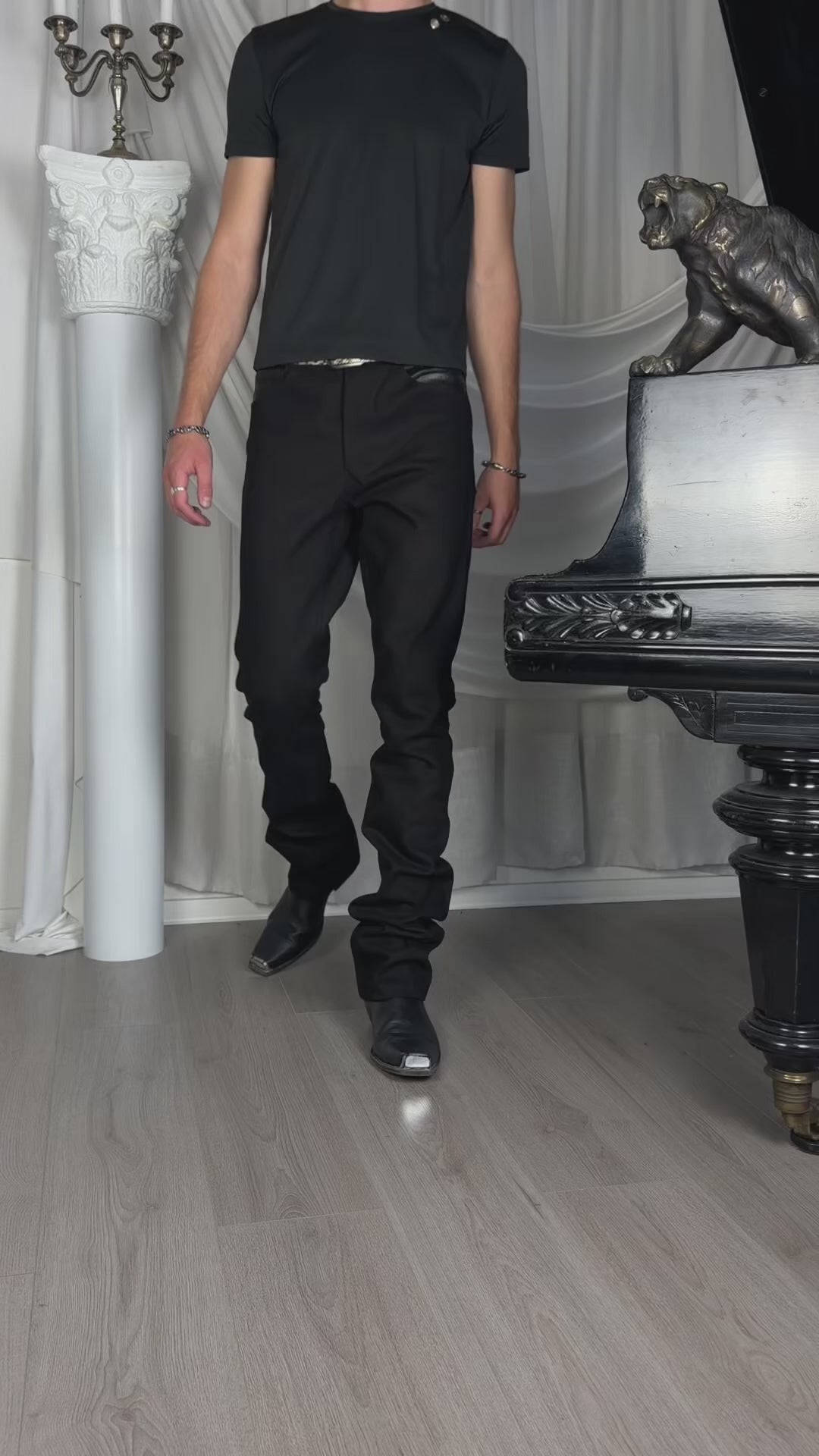 Bootcut Denim — video, model in a black T-shirt walking past a white column and a piano